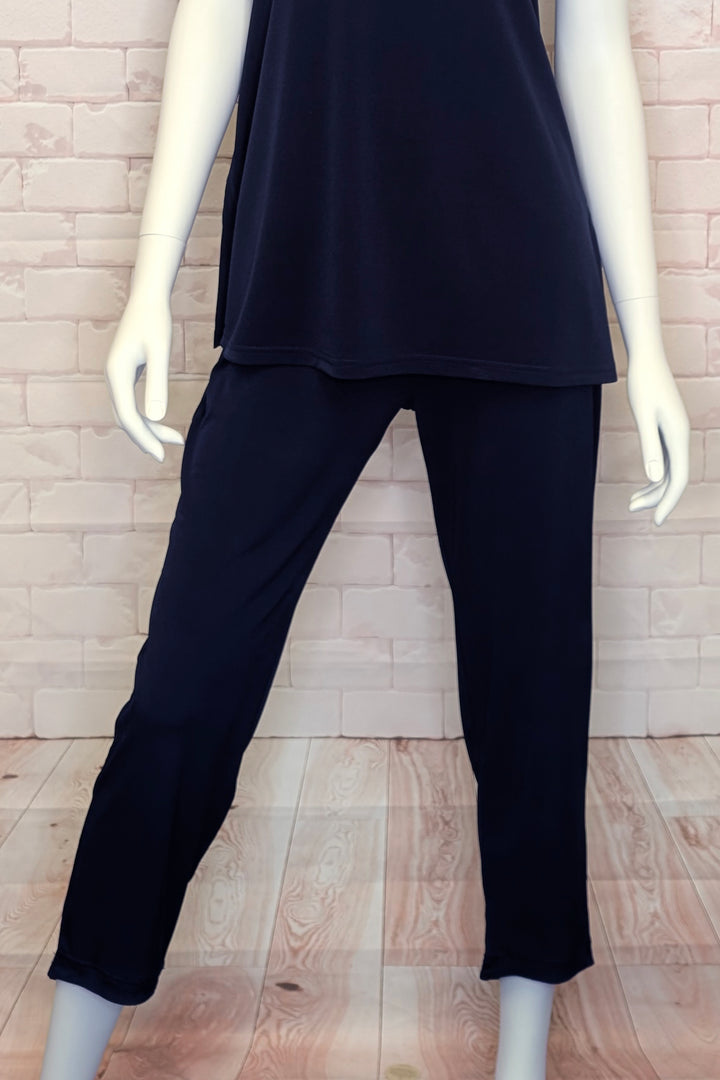 A mannequin wearing a dark navy top and matching pants standing in front of a light brick background. 