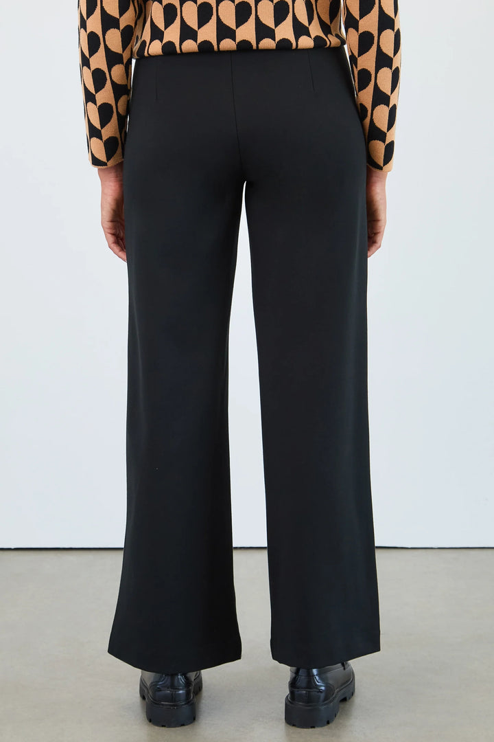 Person wearing black wide-leg pants with a patterned top against a white background