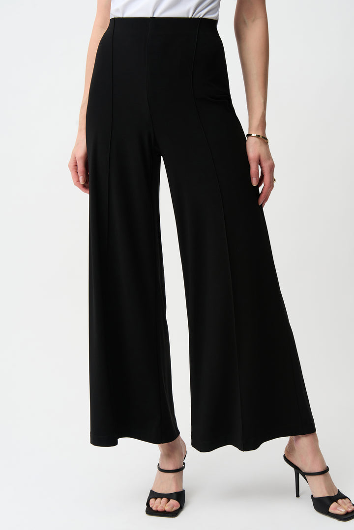 Person wearing black wide-leg pants on a white background