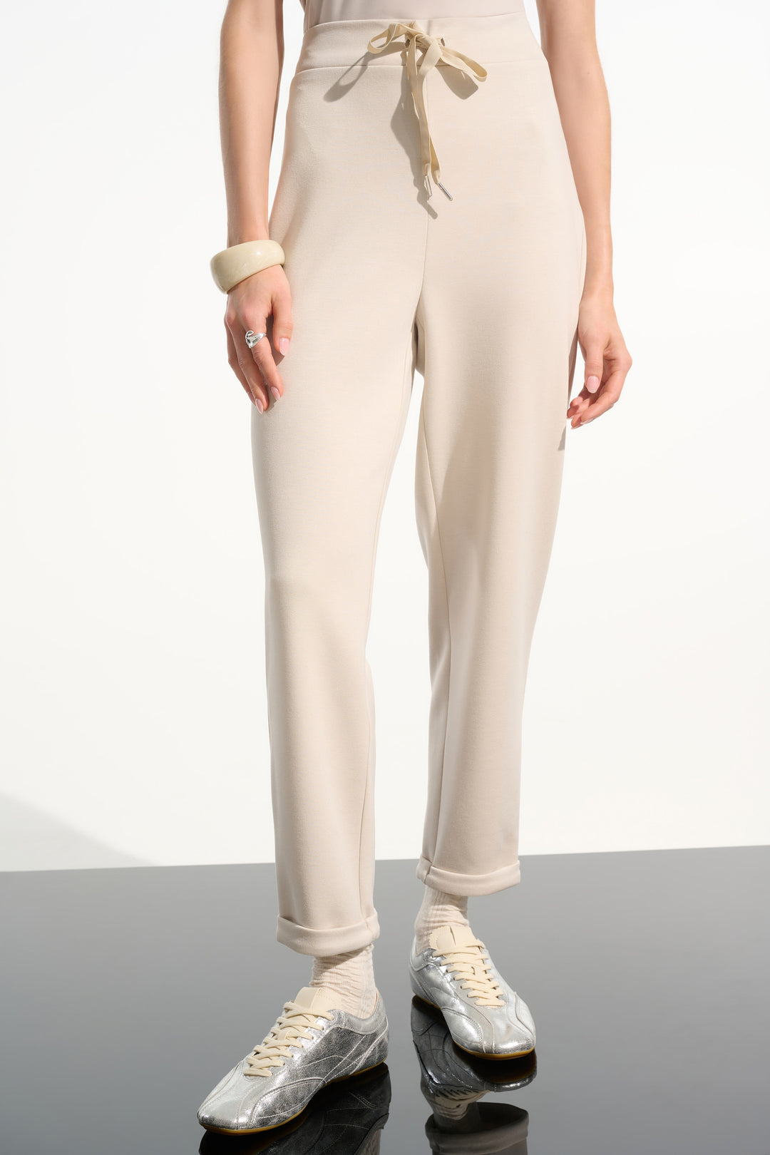 Person wearing beige jogger pants with a white background