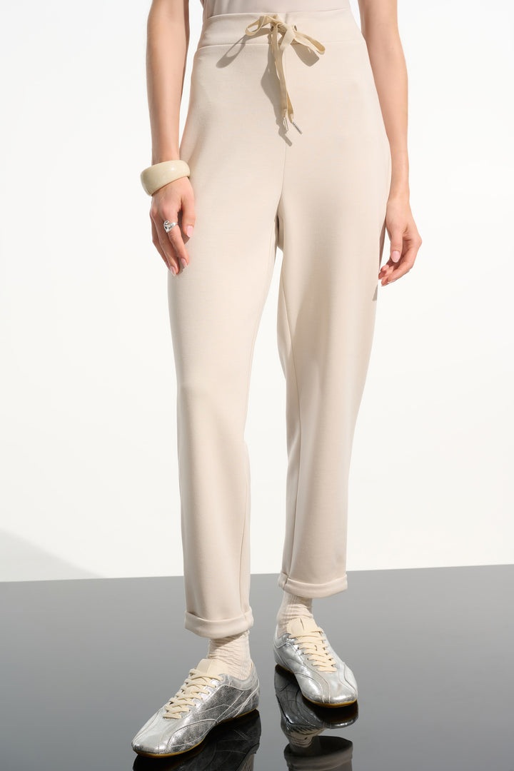 Person wearing beige jogger pants with a white background