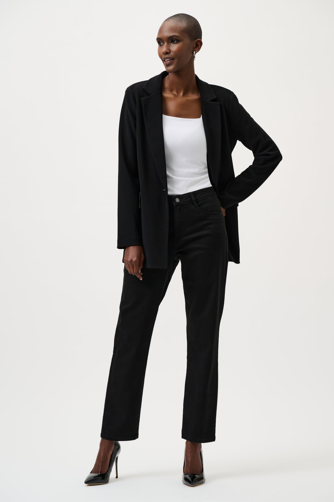Person wearing a black suit jacket, black jeans and a white top on a white background