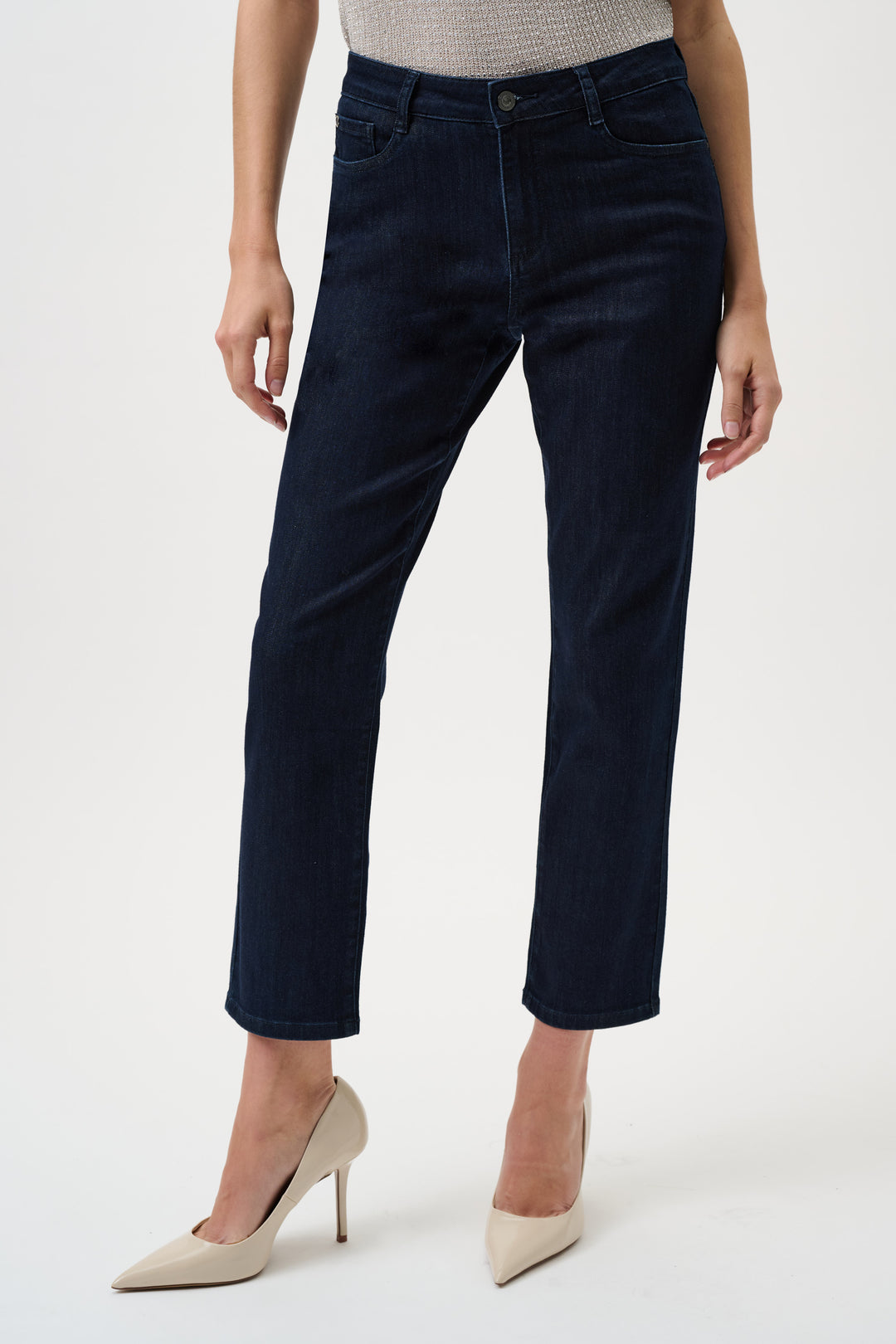 Person wearing dark blue jeans and beige heels on a white background