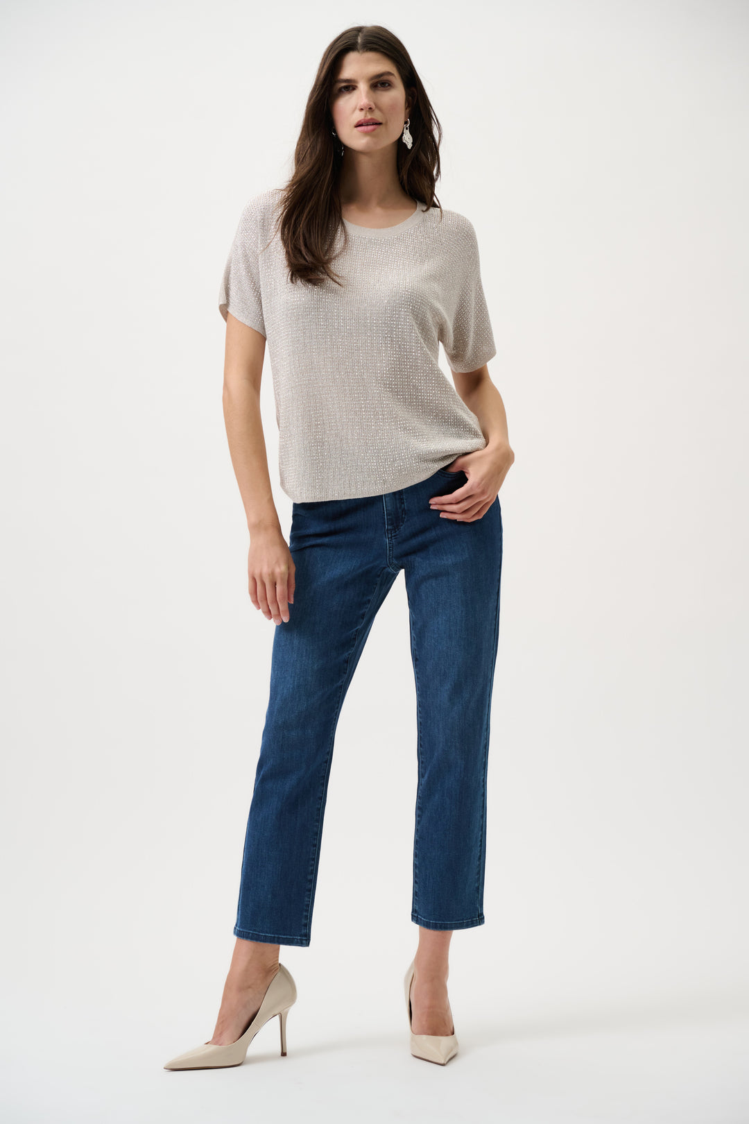 Woman wearing a light gray t-shirt and blue jeans on a white background