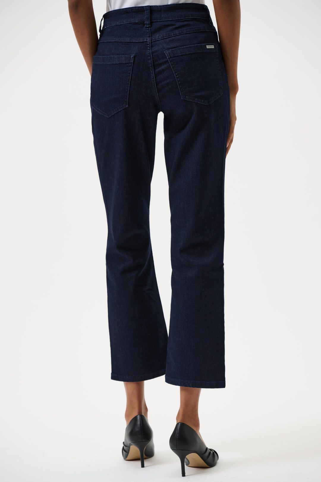 Navy blue jeans worn by a person on a white background