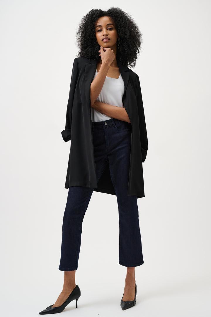 Woman wearing a black coat, white top, and dark jeans on a white background