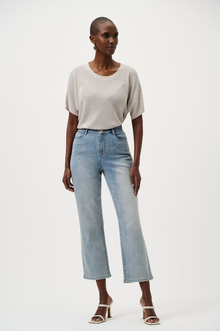 Woman wearing a light gray top and blue jeans on a white background
