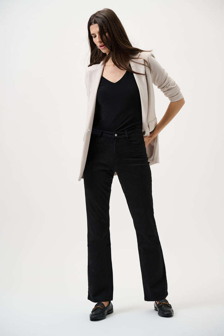 Woman wearing a beige blazer, black top, and black jeans on a white background