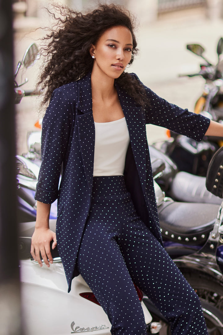 Frank Lyman Fall 2025 
This navy long blazer combines a notch lapel collar and 3/4 straight sleeves for a sleek, modern silhouette. Adorned with glitter studs all around, it elevates your business attire with a refined sparkle.