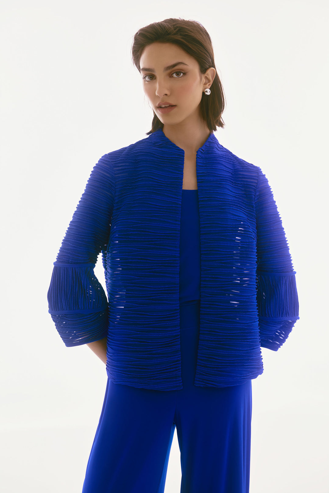 Woman wearing a blue textured jacket and pants on a white background