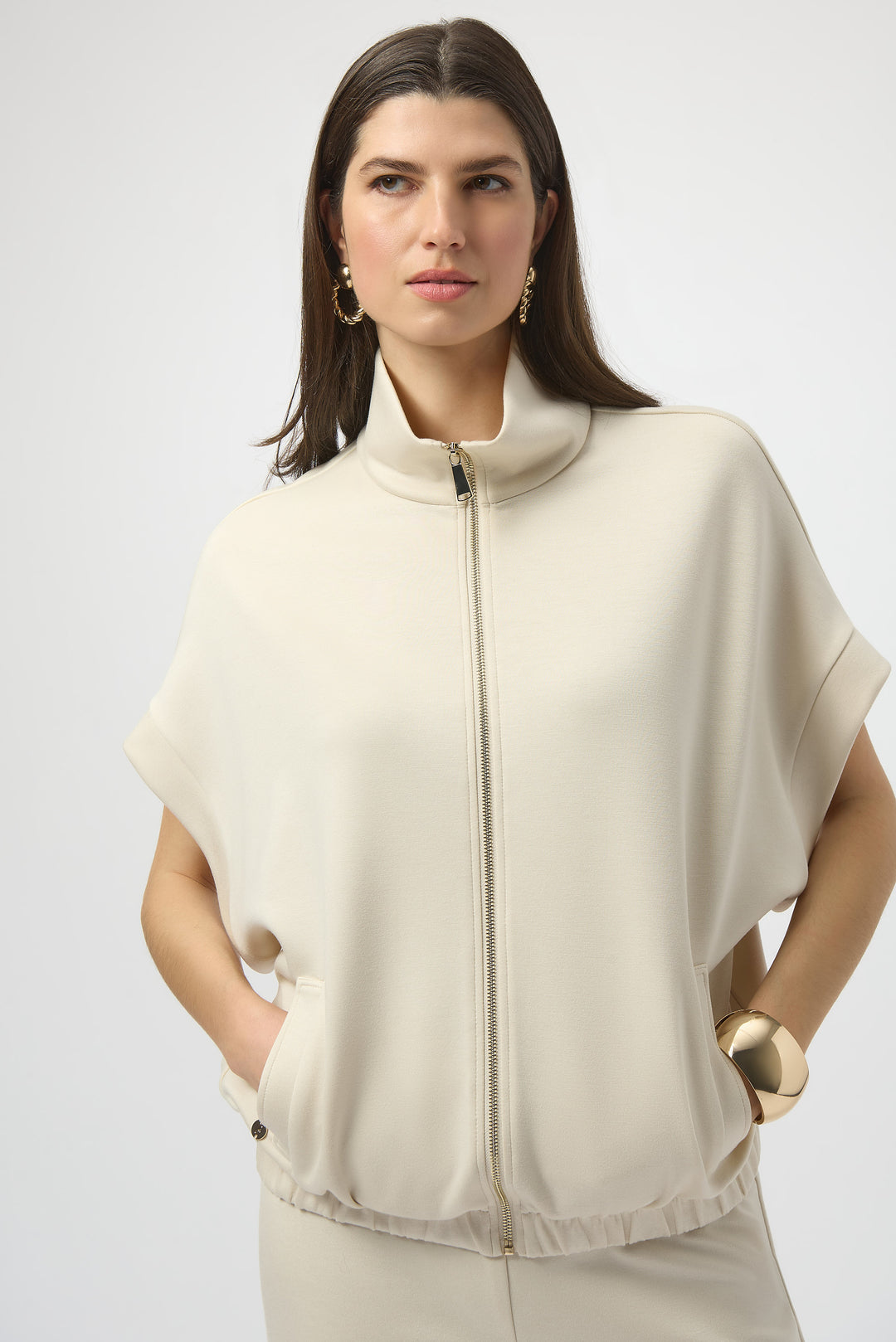 Woman wearing a beige light zip jacket  against a white background