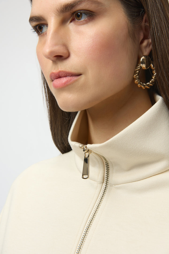 Close-up of a person wearing a beige jacket with a gold zipper and hoop earrings.