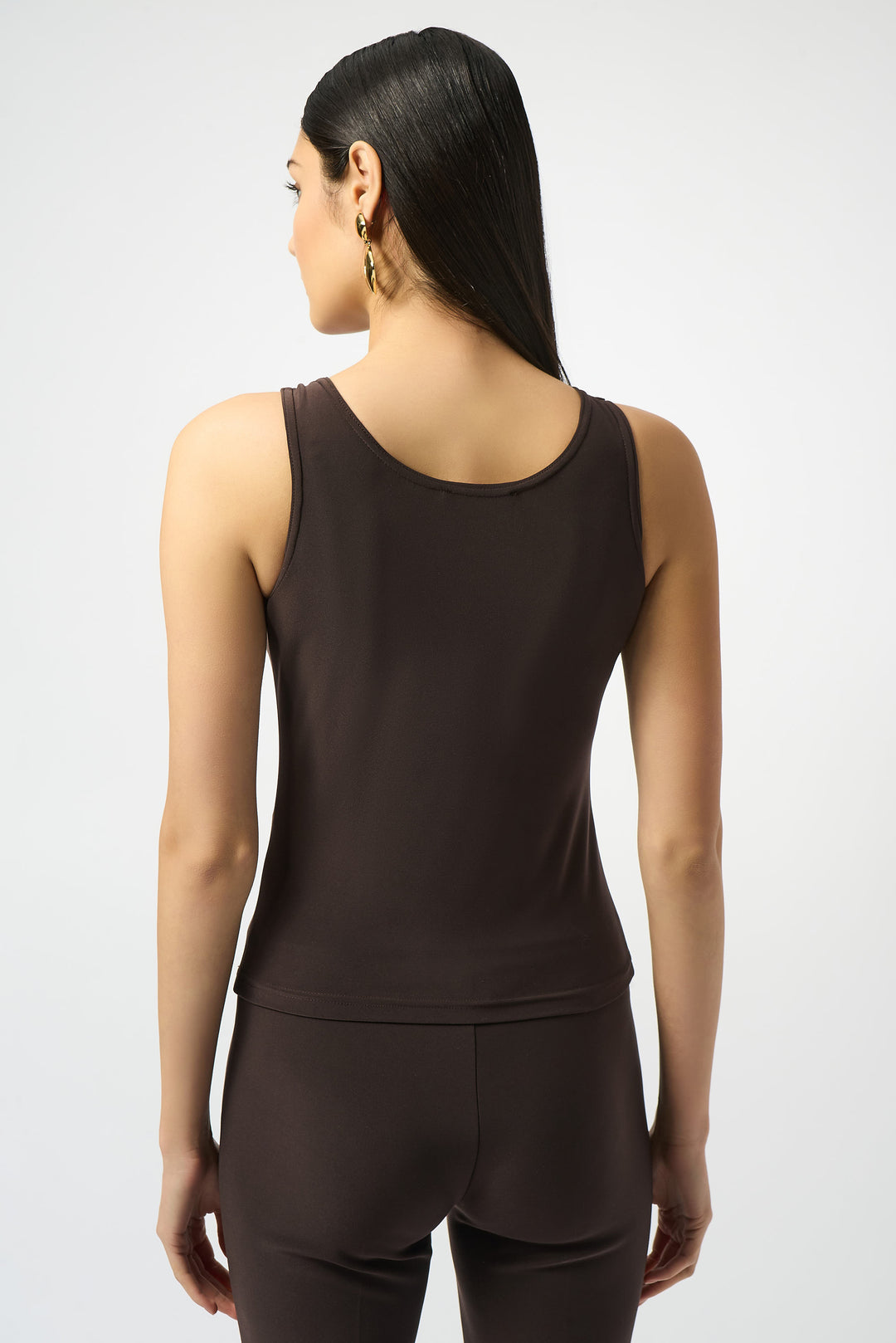 Woman wearing a brown tank top and pants on a light gray background