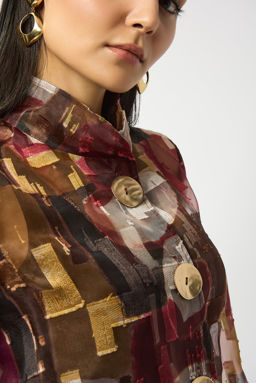 Close-up of a person wearing a patterned garment with gold buttons on a white background