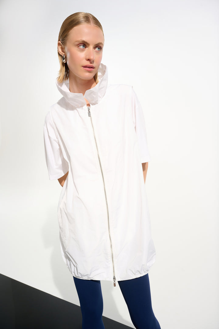 Woman wearing a white light long vest with a front zipper on a plain background