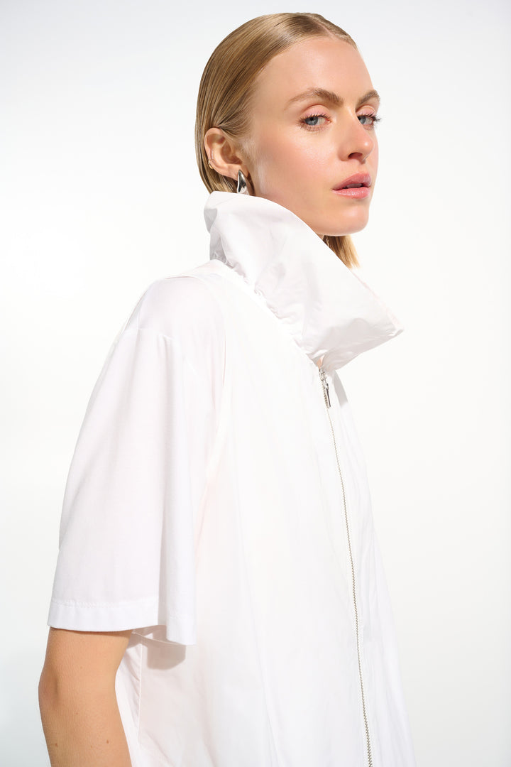 Person wearing a white high-neck light long vest on a plain background