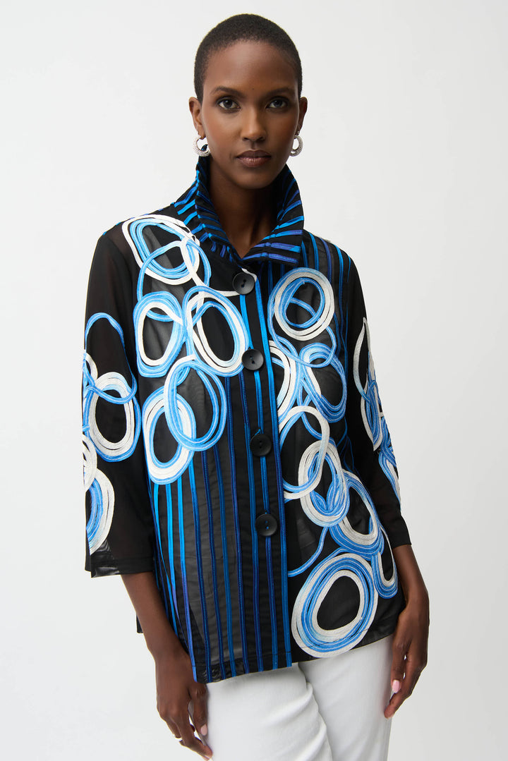 Woman wearing a black button jacket with blue and white circular patterns on a white background