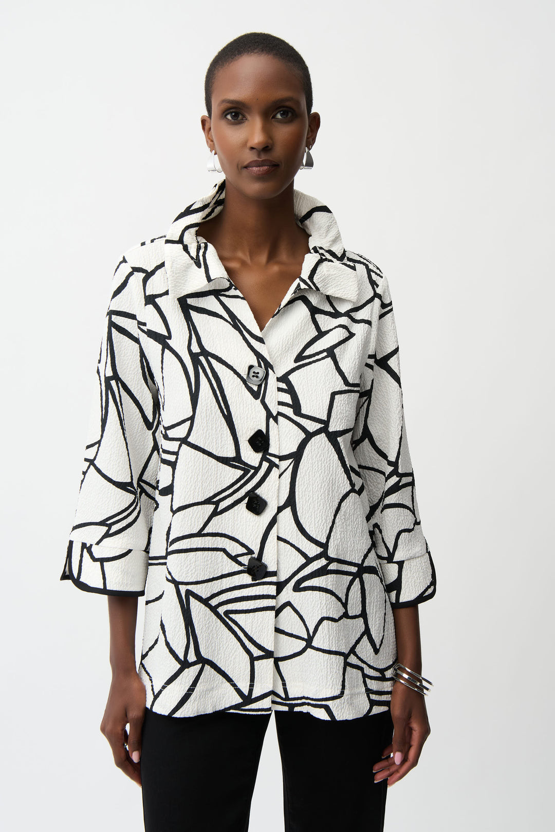 Woman wearing a black and white patterned light jacket with buttons against a white background