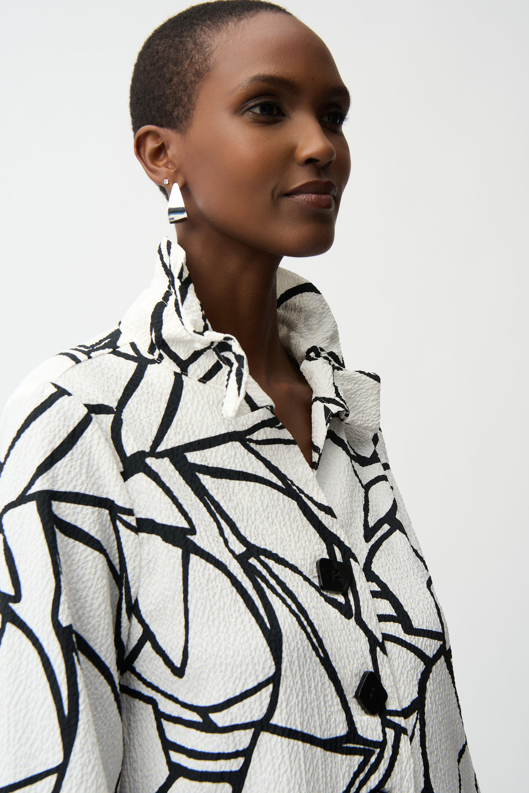 Woman wearing a black and white patterned coat against a plain background
