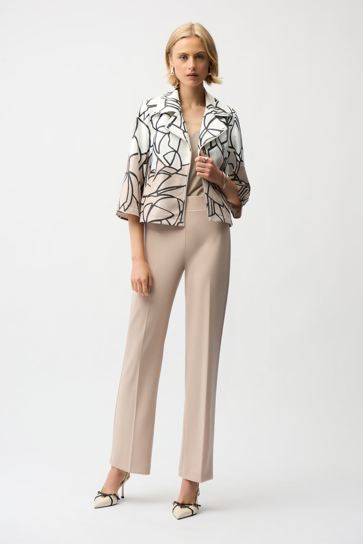 Woman wearing an abstract print zip jacket and beige pants on a white background
