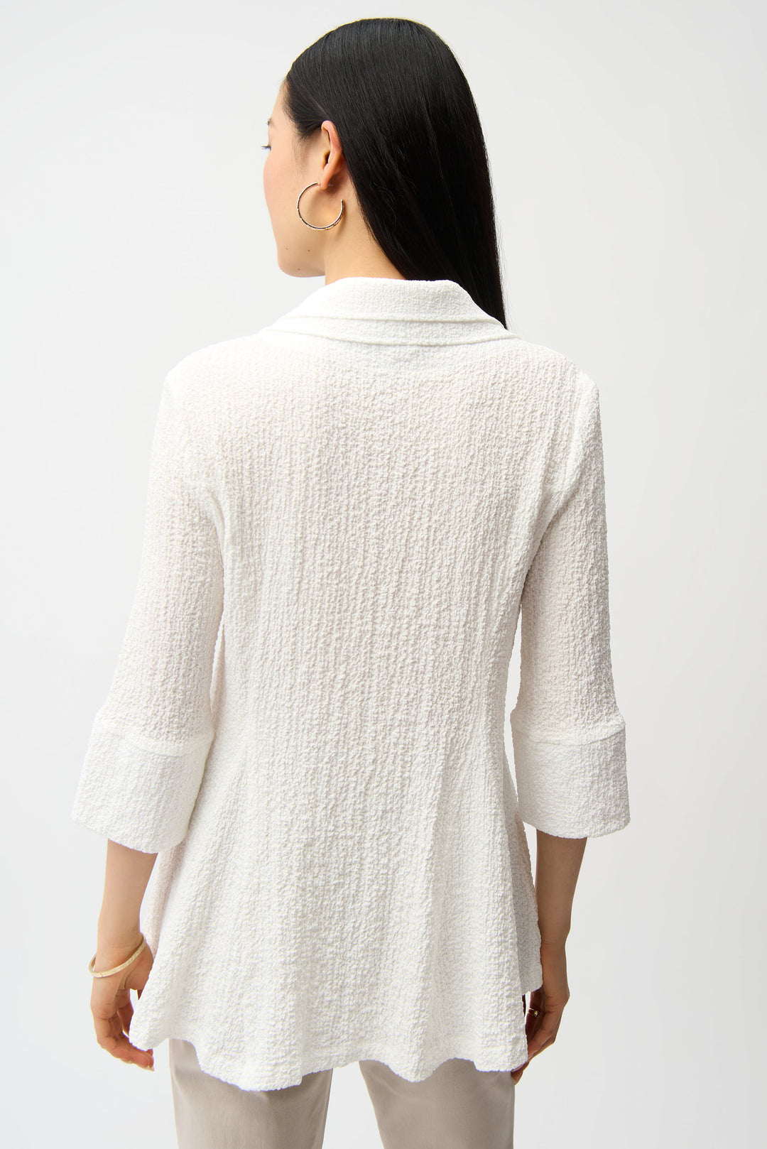 Woman wearing a textured white blouse against a plain background