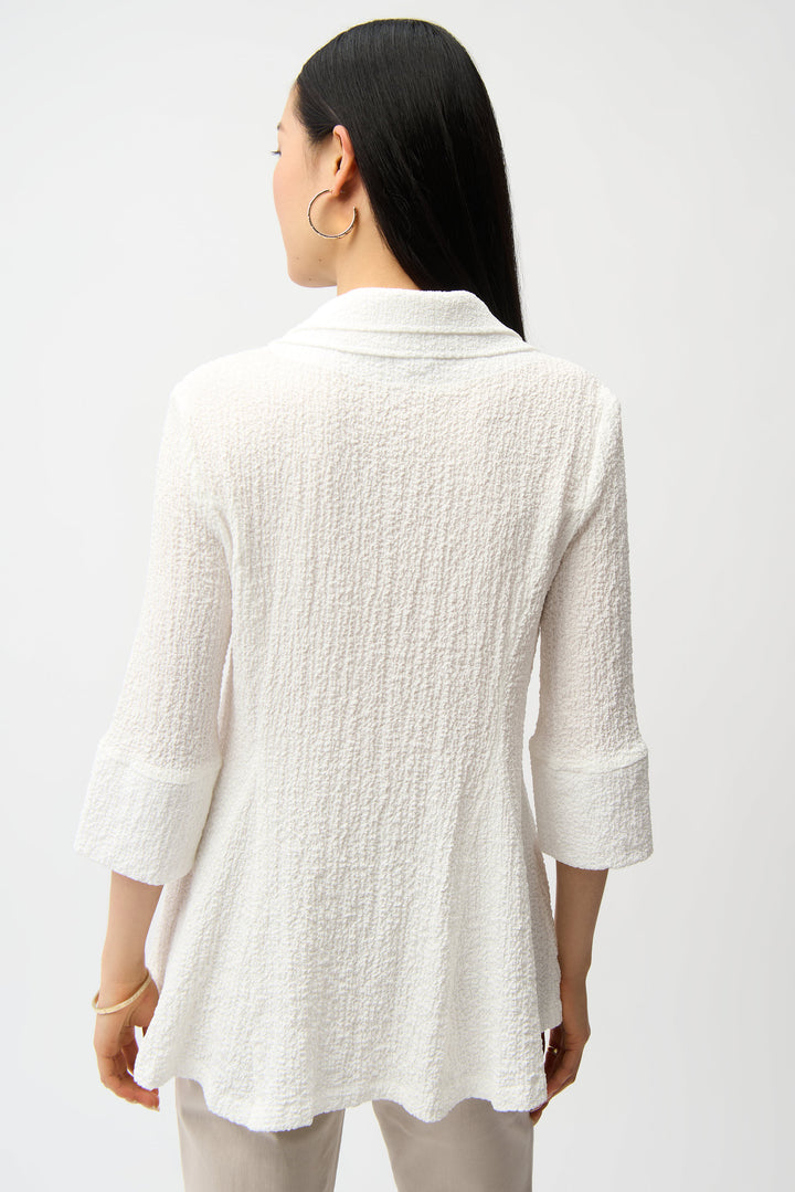 Woman wearing a textured white blouse against a plain background