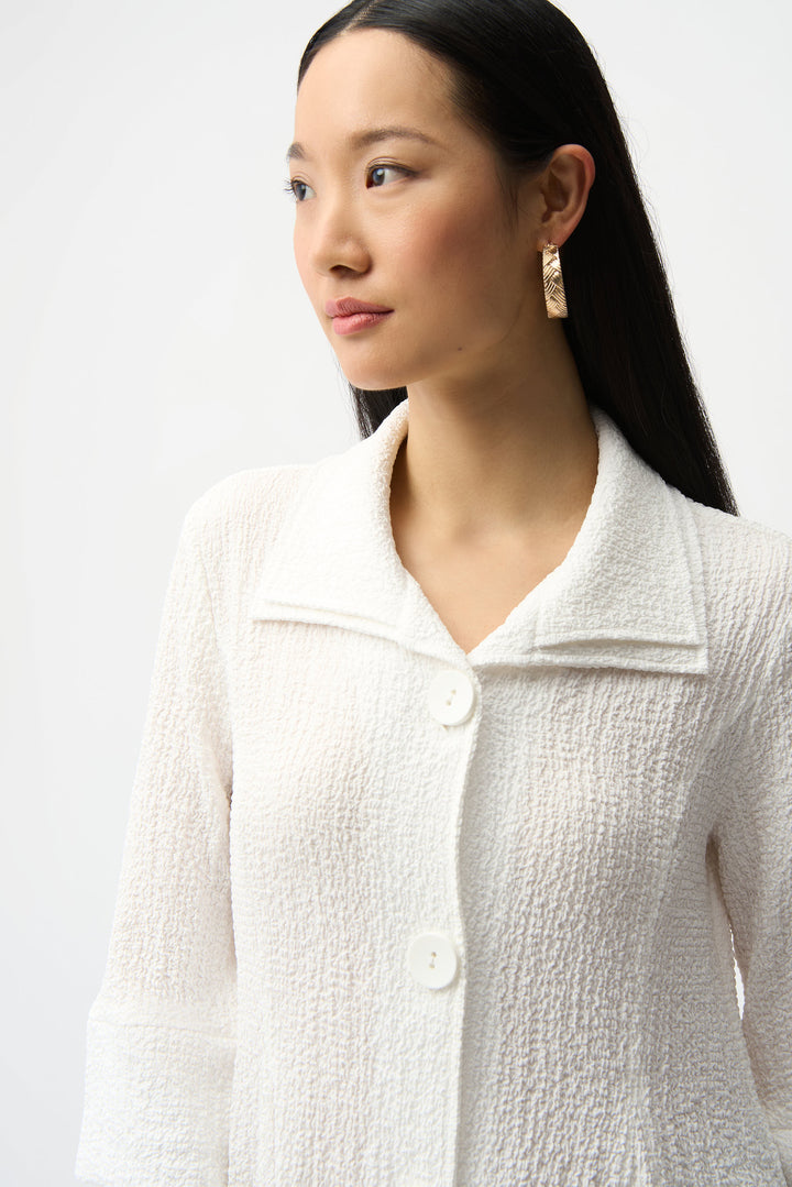 Woman wearing a white textured jacket against a plain background