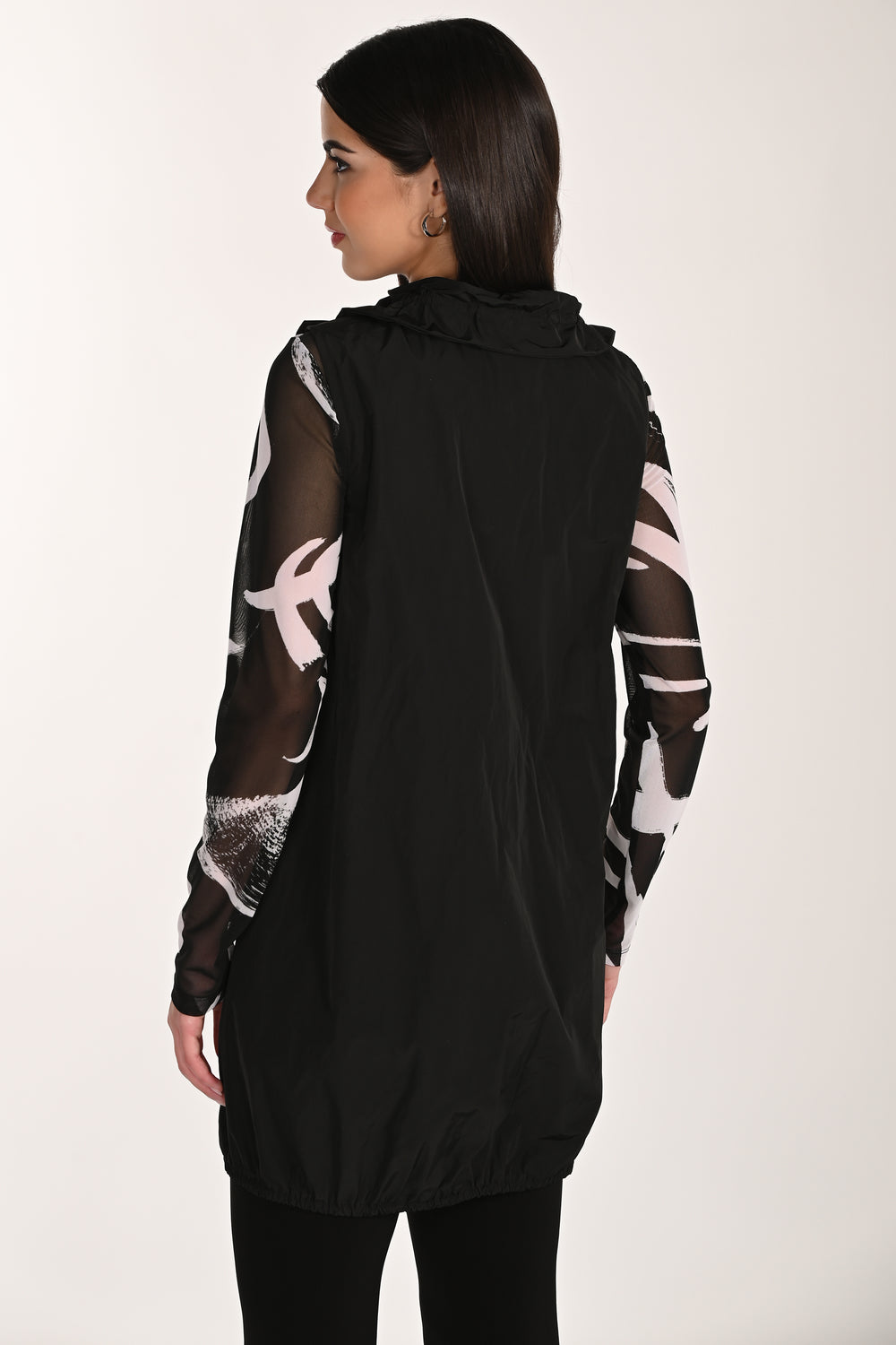 Woman wearing a black long zipper vest with sheer sleeves on a white background