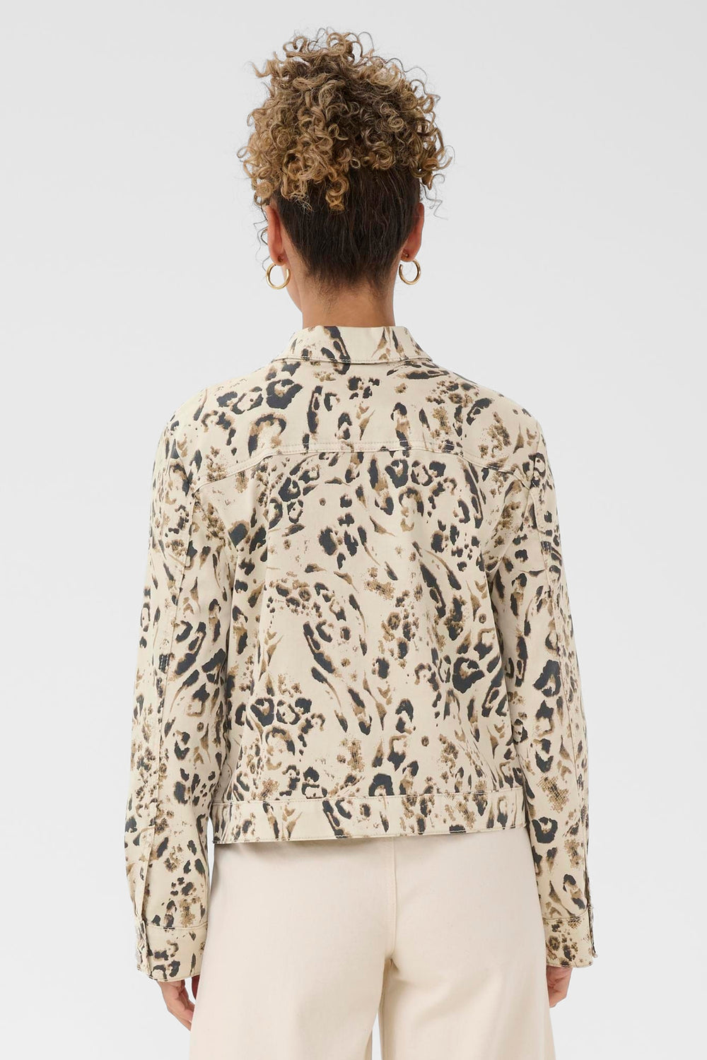 Person wearing a leopard print jean jacket on a plain background