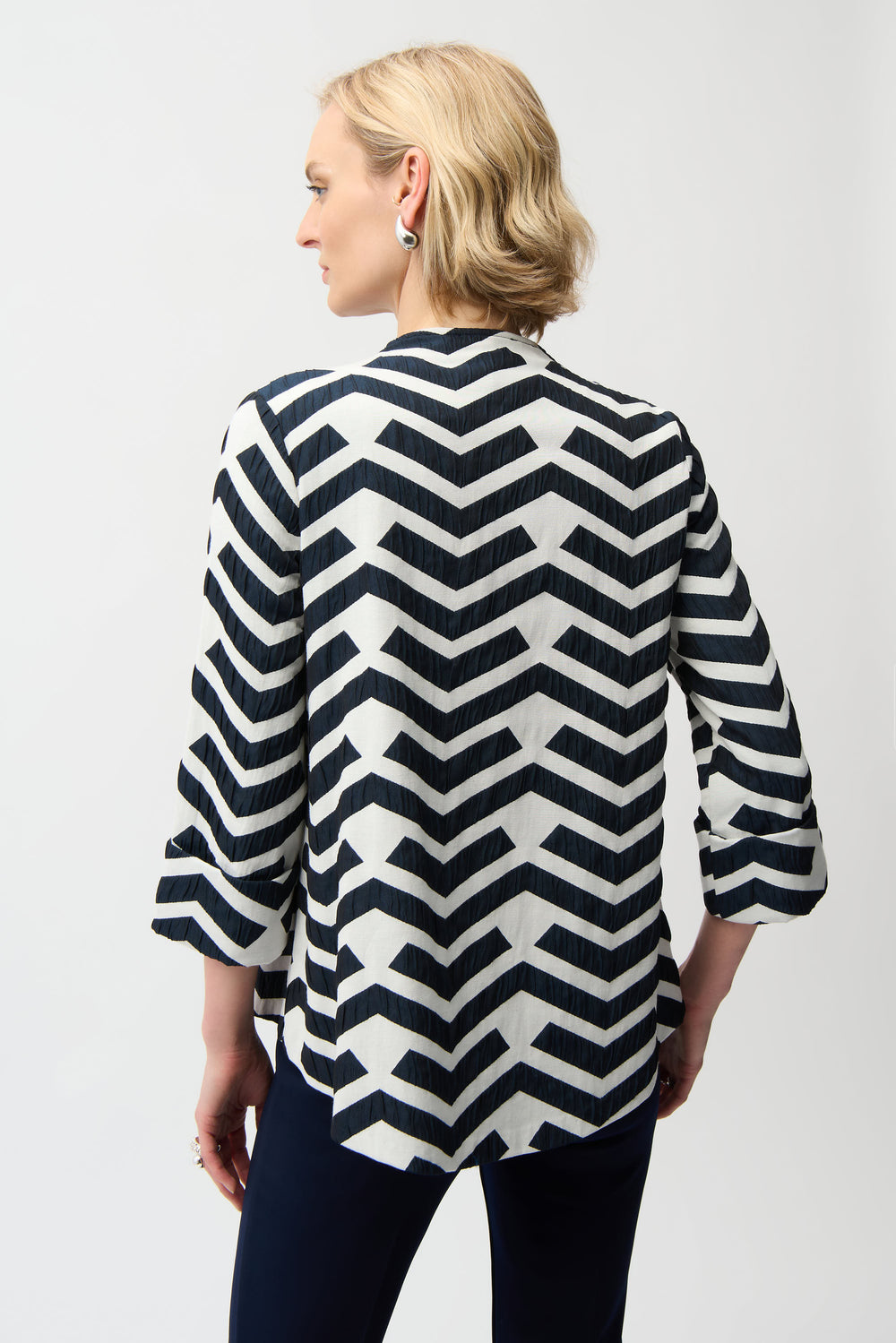 Woman wearing a black and white chevron patterned top on a white background