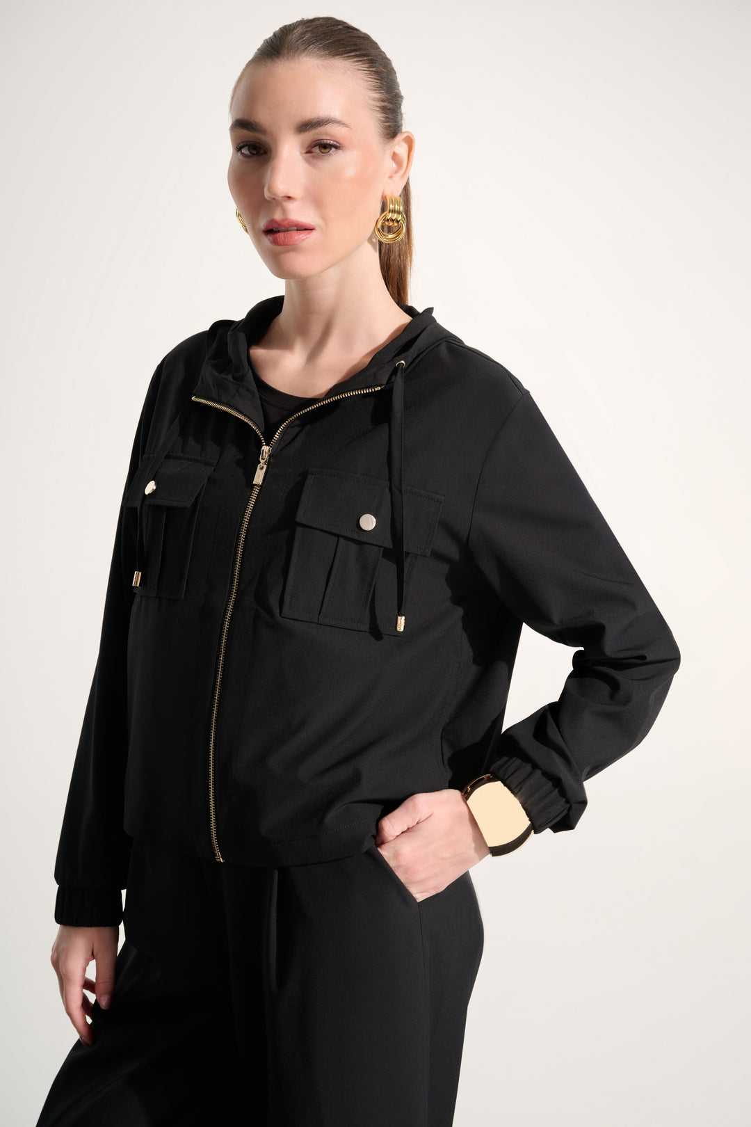 Woman wearing a black jacket with gold zippers on a white background