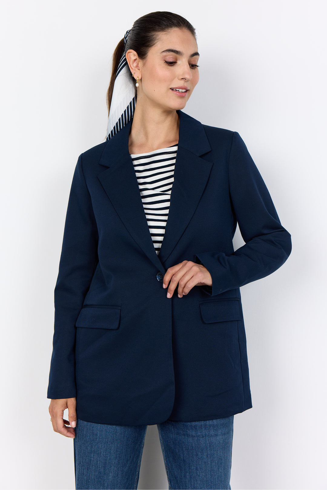 Woman wearing a navy blazer over a striped shirt on a white background