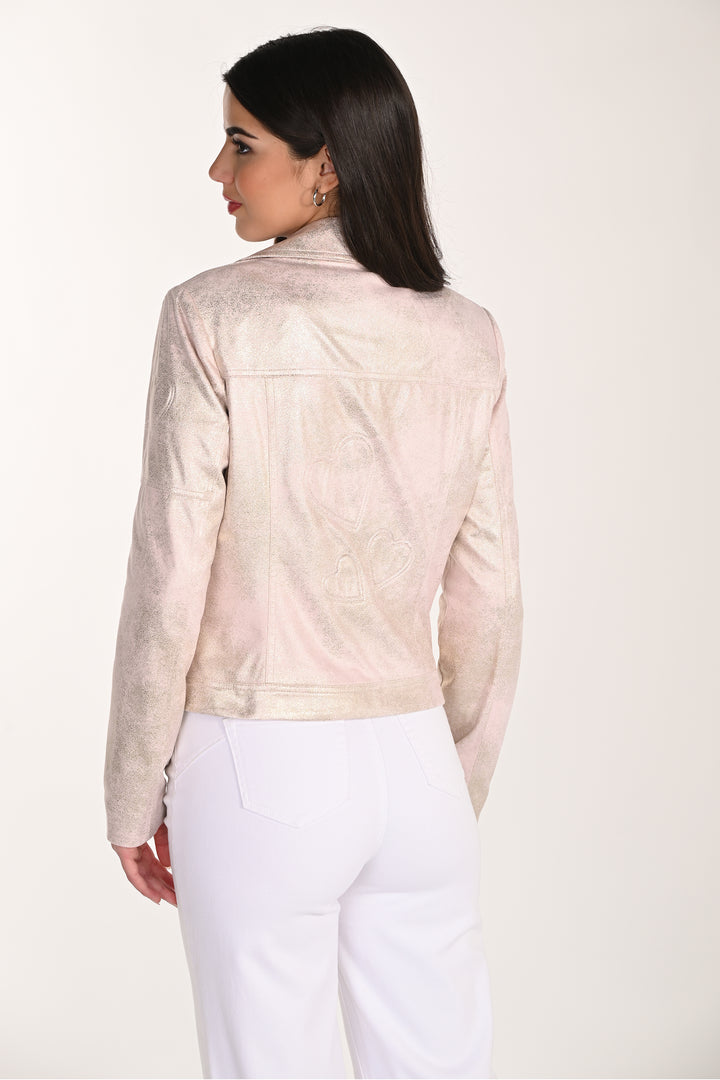 Woman wearing a light pink leather jacket and white pants on a white background