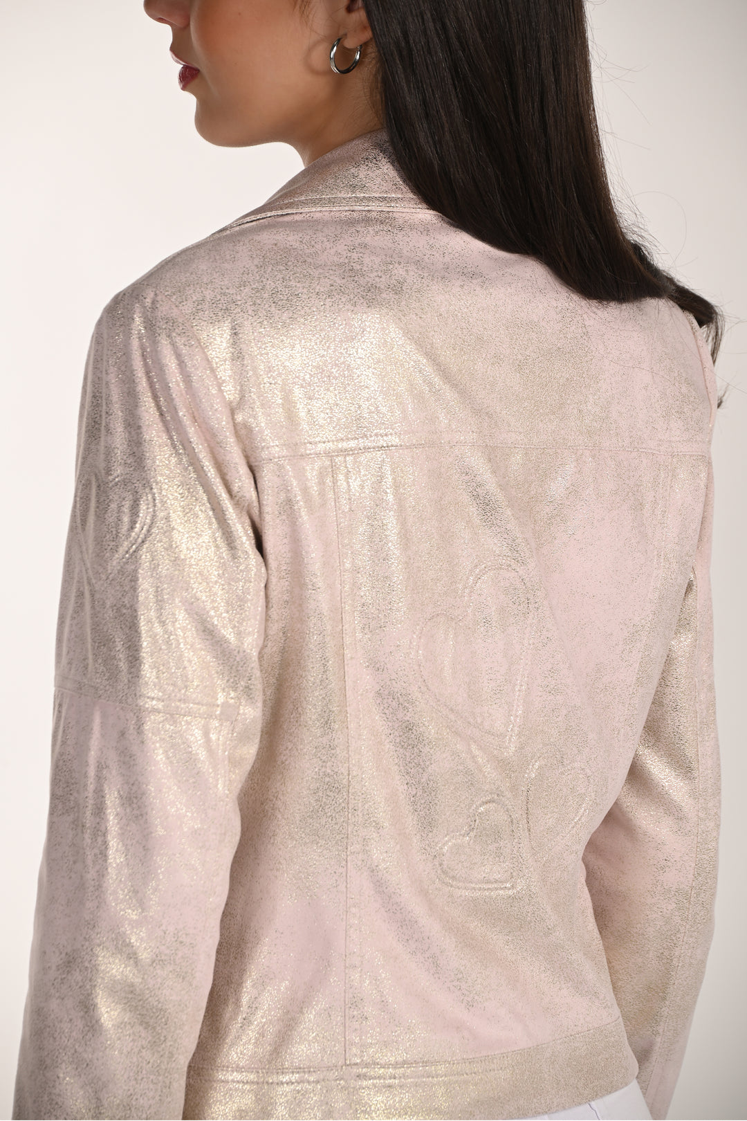 Close-up of a person wearing a light-colored traditional outfit with intricate patterns.