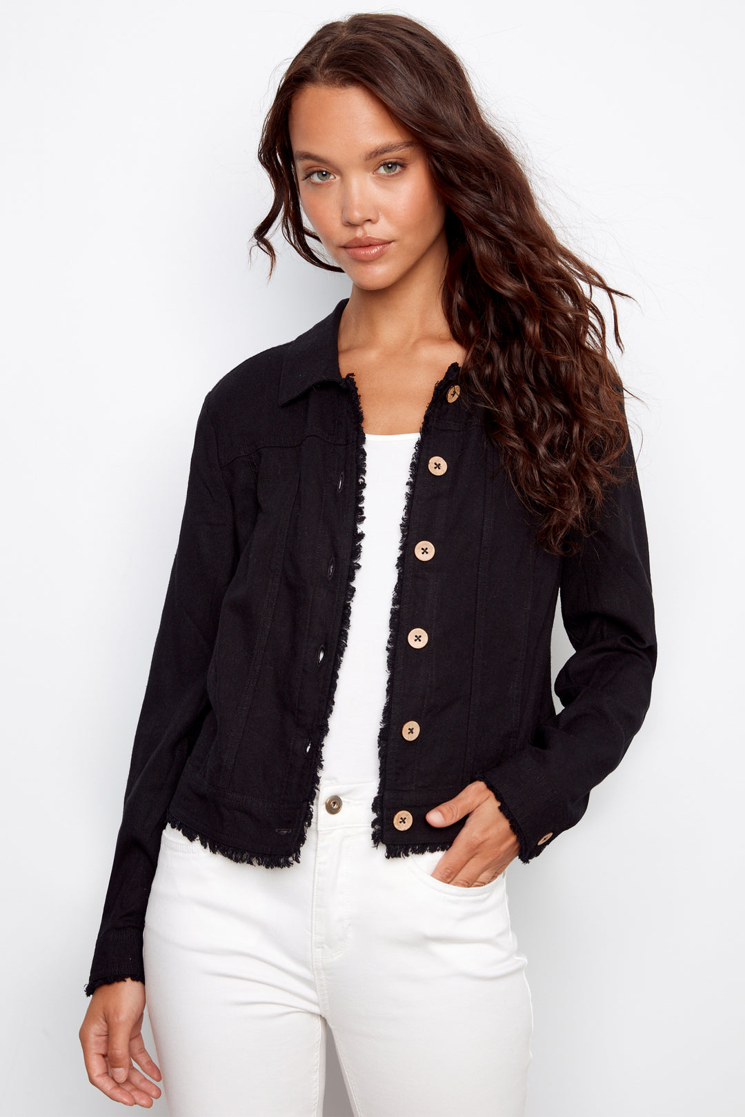 Woman wearing a black denim jacket with frayed edges with contrast buttons on a white background
