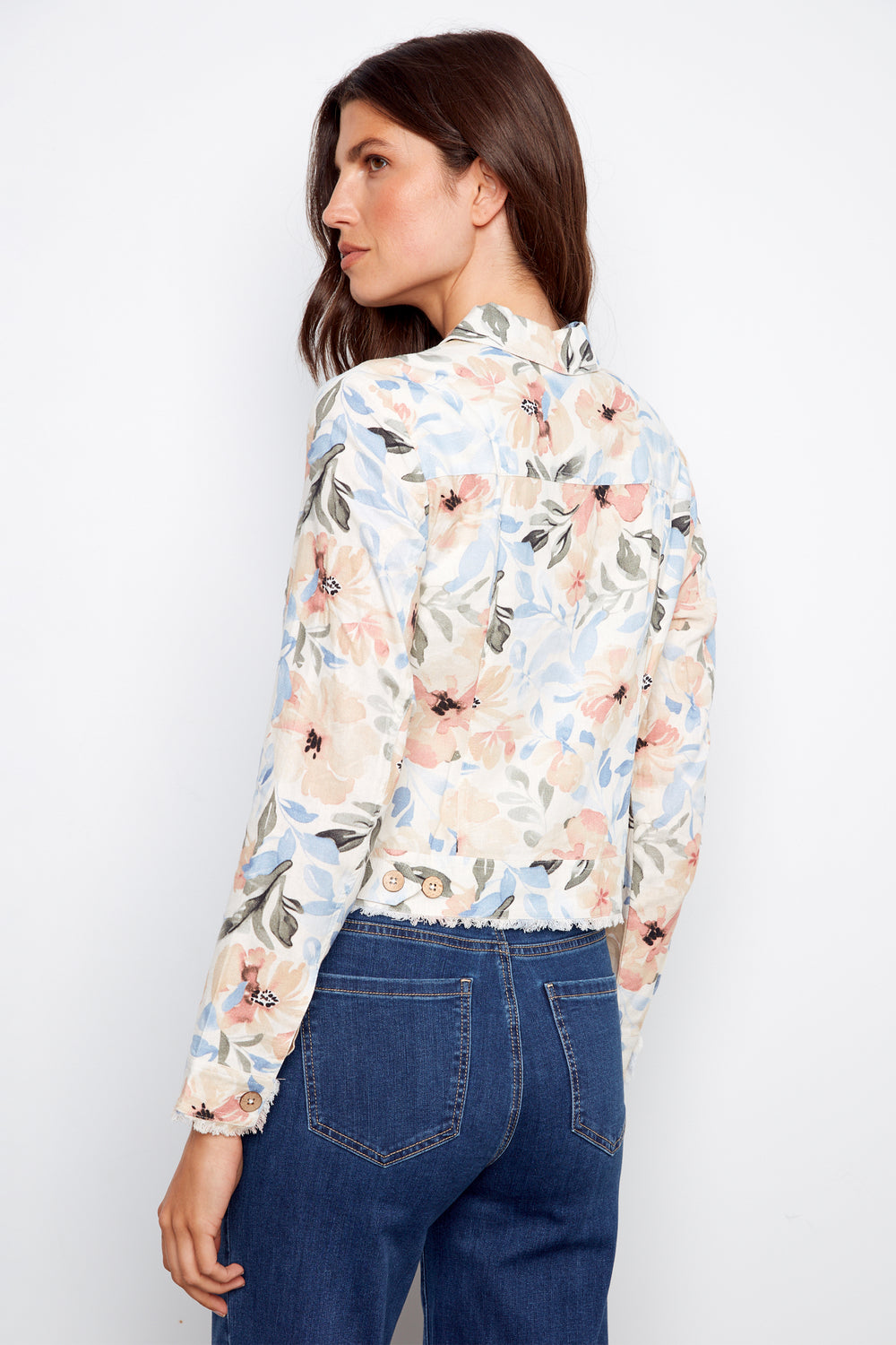 Woman wearing a floral light jacket and blue jeans against a white background