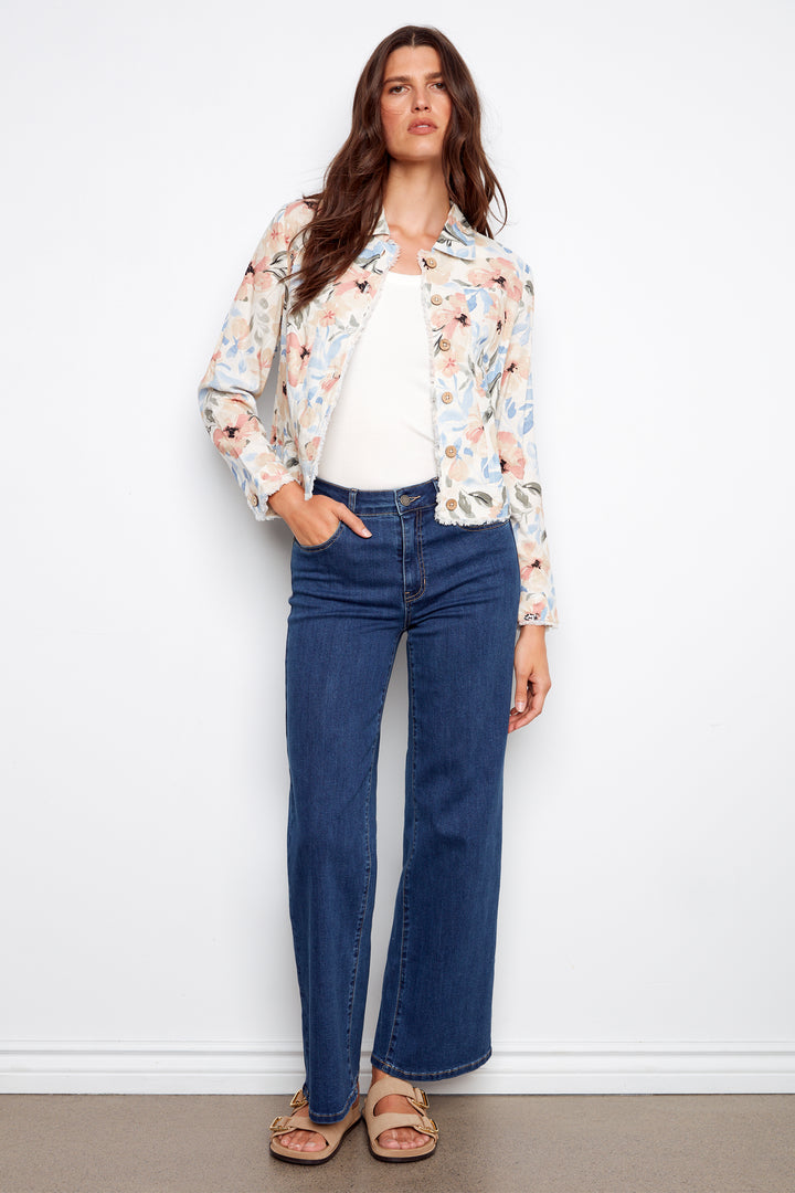 Woman wearing a floral light jacket and blue jeans against a white background