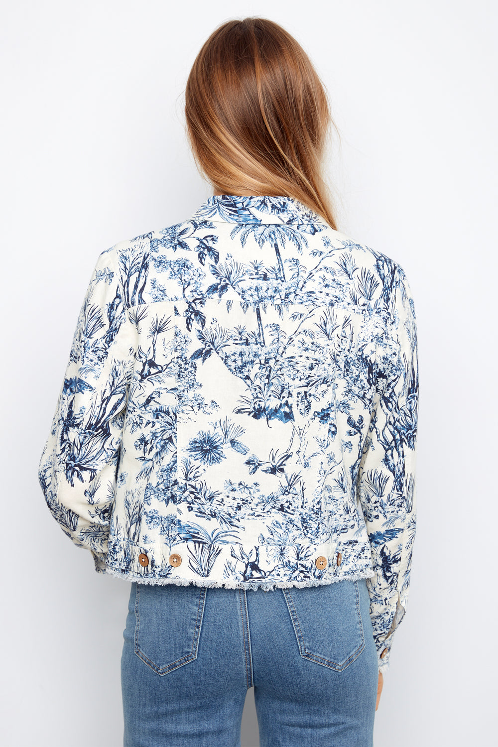 Person wearing a blue floral patterned shirt and jeans on a white background