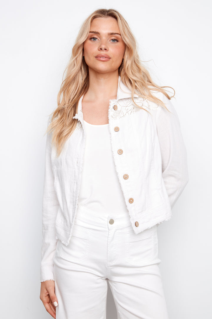 Woman wearing a white light jacket with gold buttons on a plain background