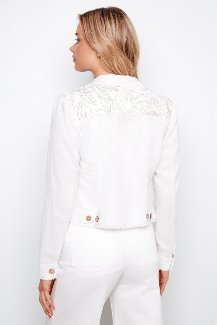 Woman wearing a white outfit with gold buttons on a plain background