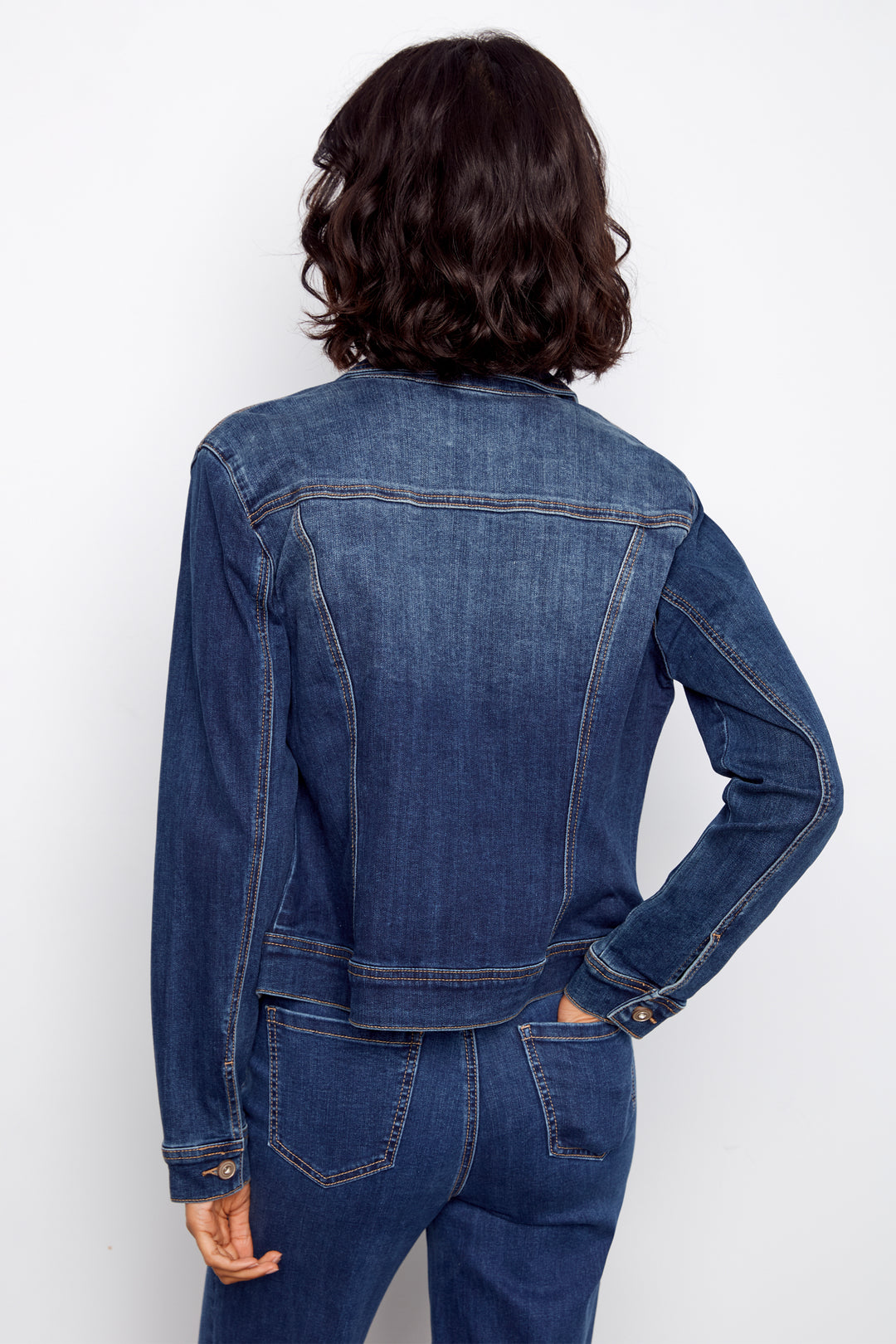 Person wearing a blue denim jacket and jeans on a white background