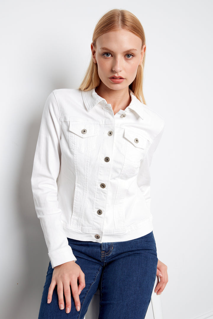 Woman wearing a white denim jacket and blue jeans on a plain background