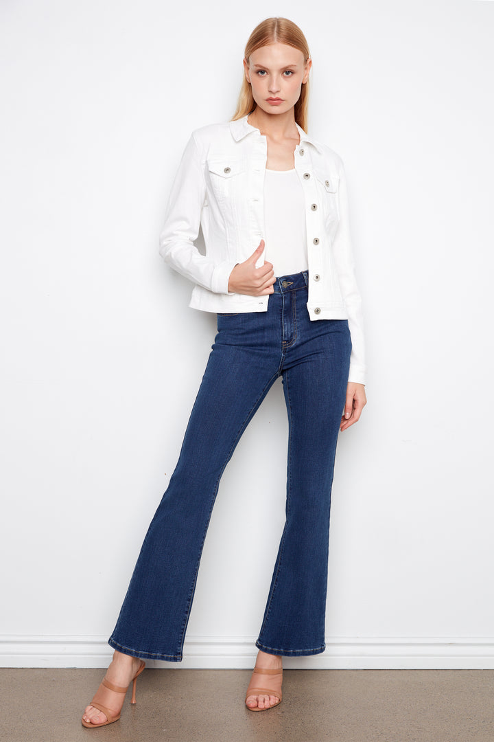 Woman wearing a white jacket and blue jeans against a white background
