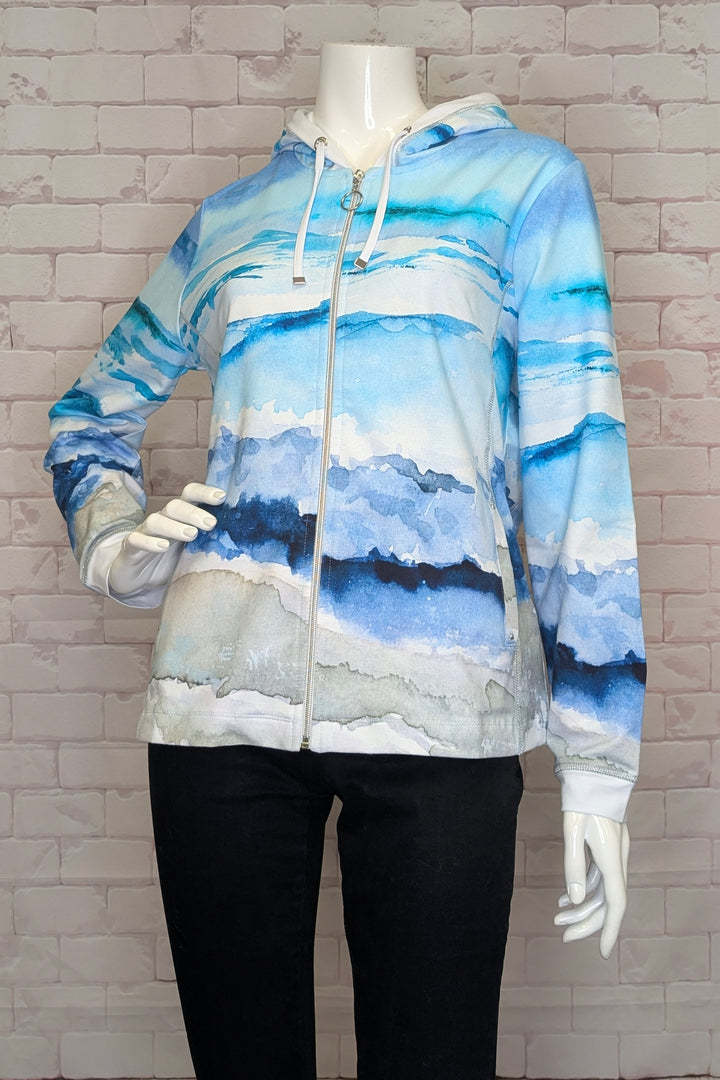 Hoodie with a blue and gray mountain design on a mannequin against a brick wall.