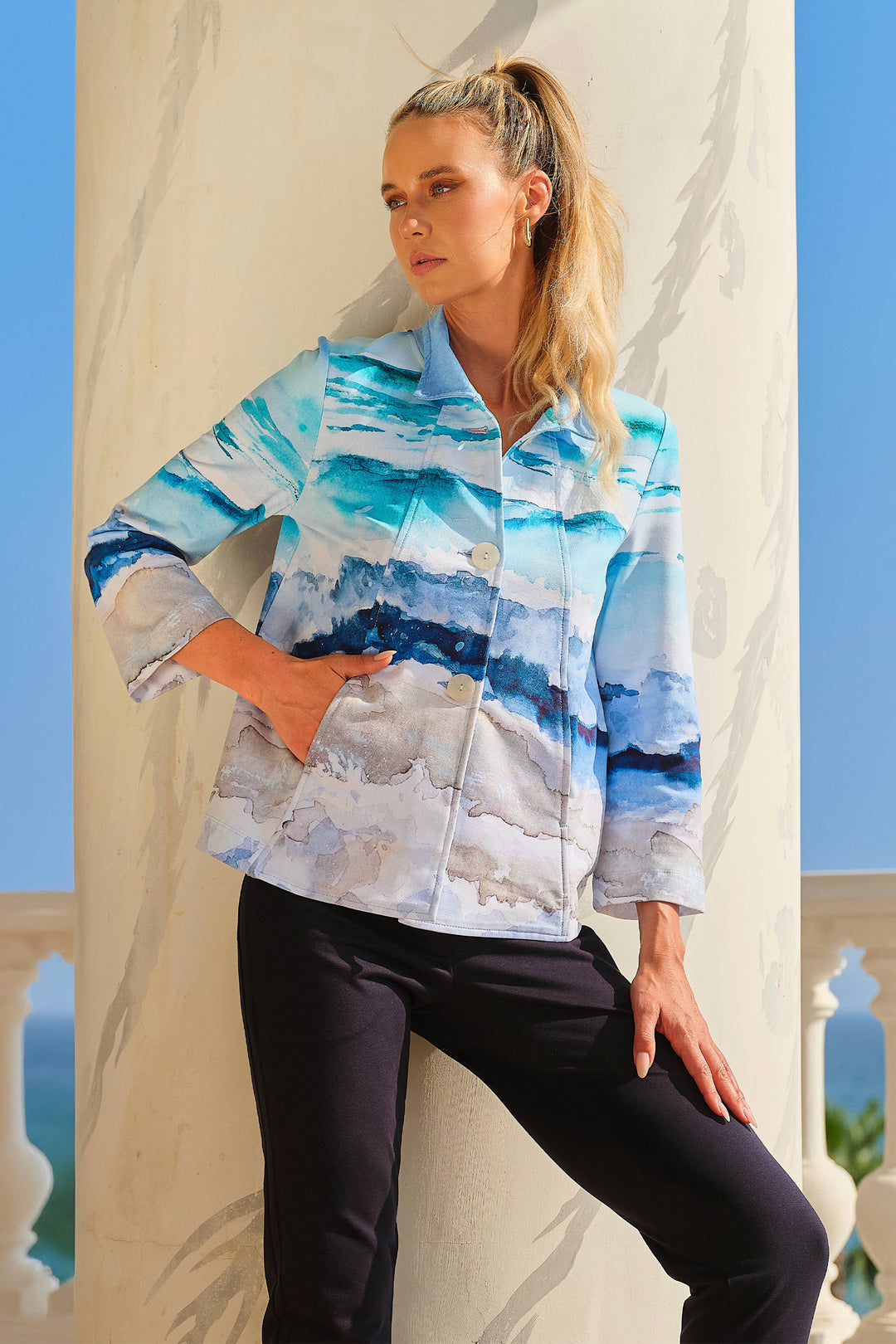 Woman wearing a colorful jacket with abstract patterns against a blue sky.