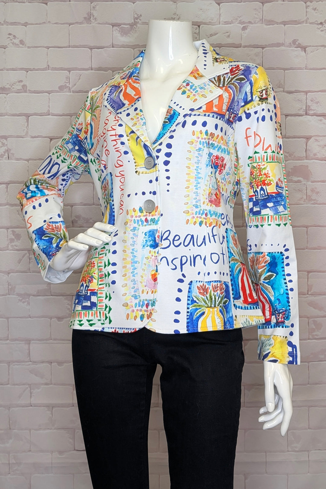 Colorful garden floral button blazer shirt on a mannequin against a gray brick wall.
