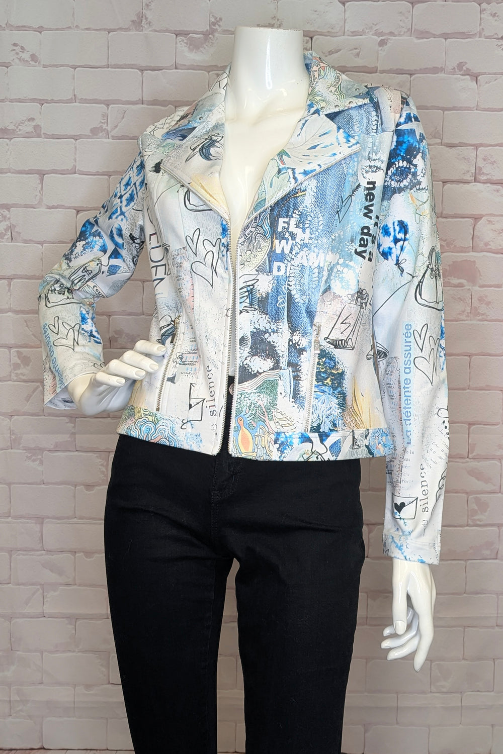 Mannequin wearing a colorful jacket with text and graphics against a light brick wall.