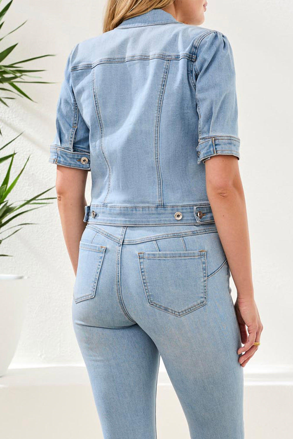Person wearing a light blue denim jumpsuit with a white background