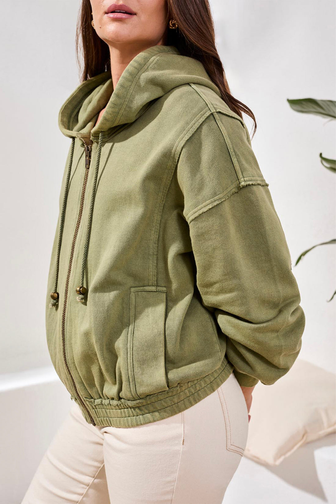 Person wearing a green hoodie with a neutral background