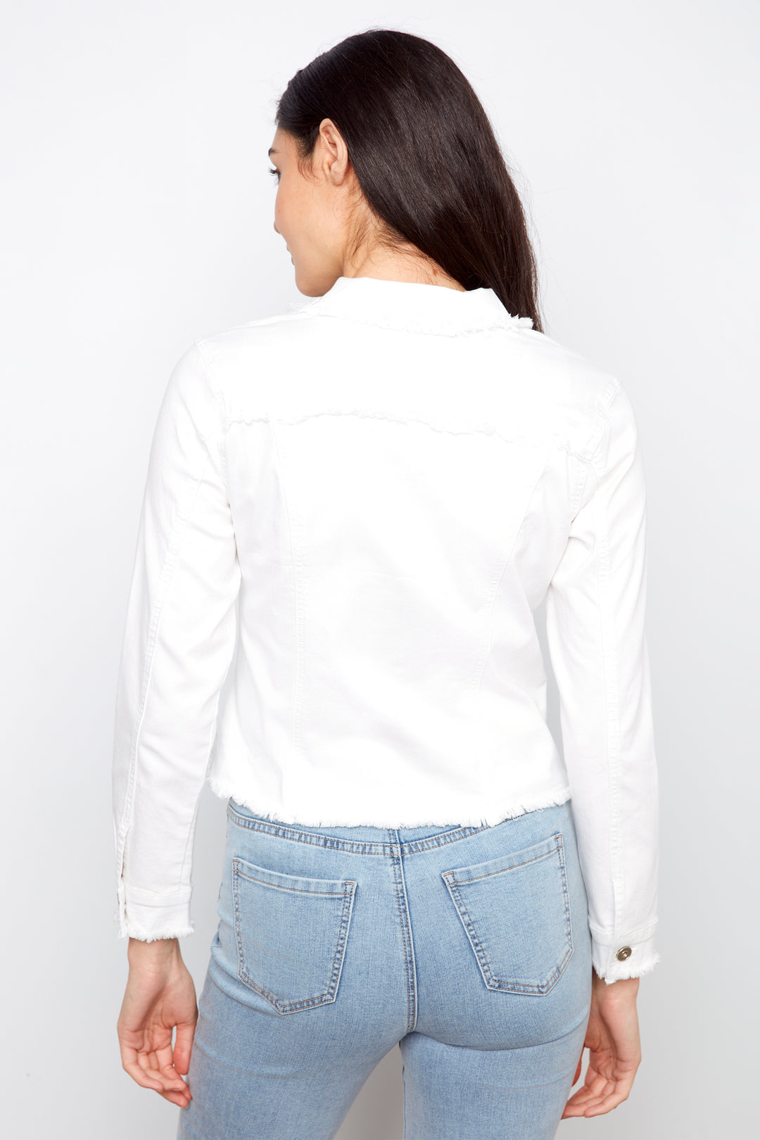 Person wearing a white shirt and light blue jeans on a plain background